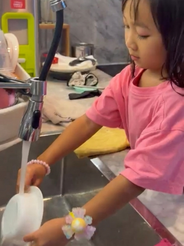 Seorang siswi TK Presiden membantu pekerjaan di rumah