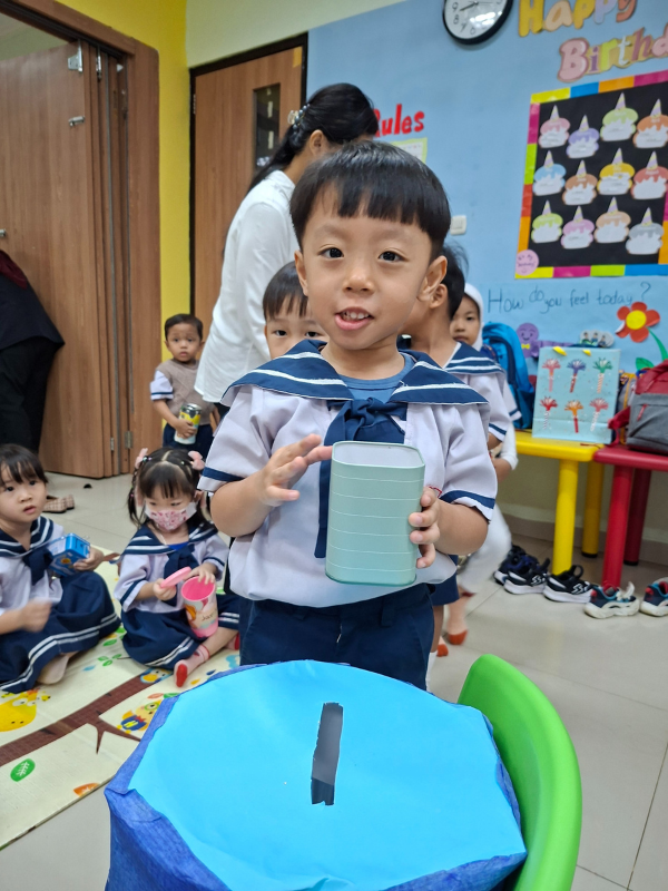 Vano, murid kelas Nursery, dengan bangga memamerkan celengannya